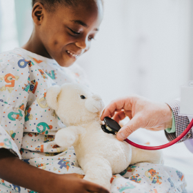 child with teddy bear getting medical check up