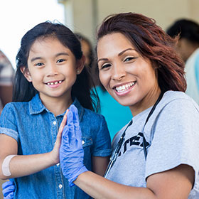 Nurse giving child highfive and looking to camera