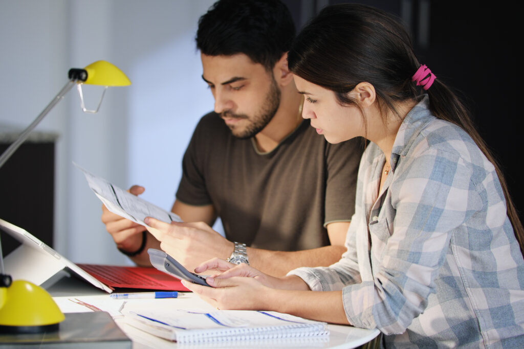 Young couple reviewing invoices and doing calculations.