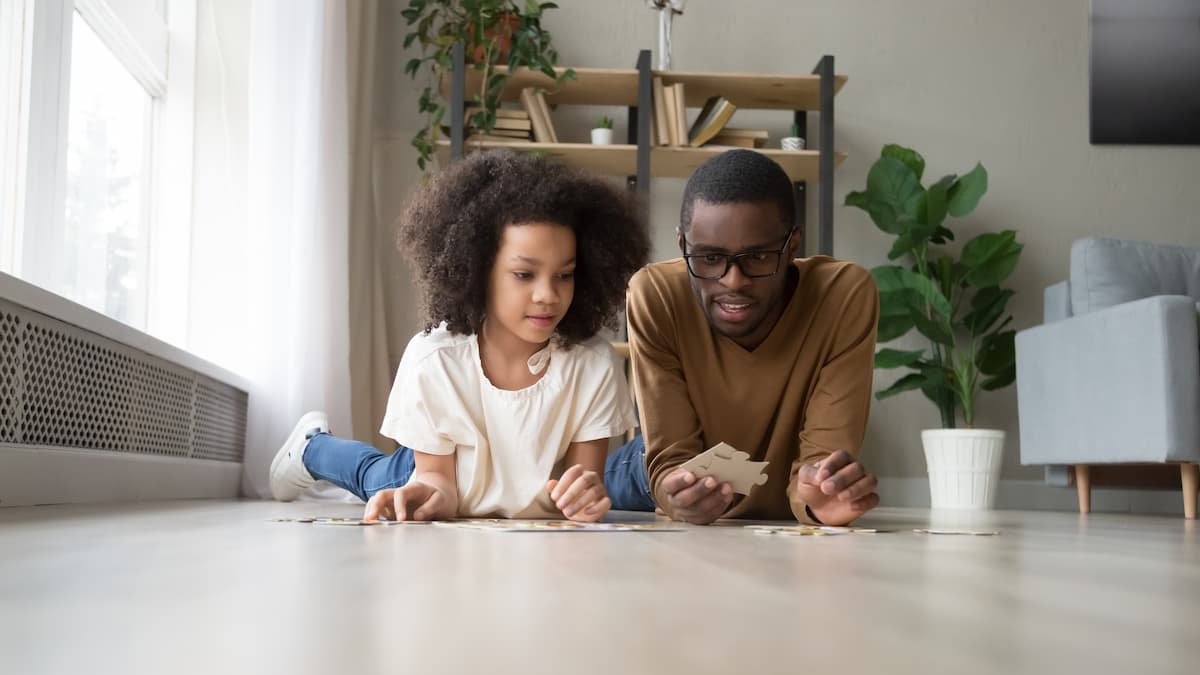 Dad and girl at home sitting on floor playing with puzzle