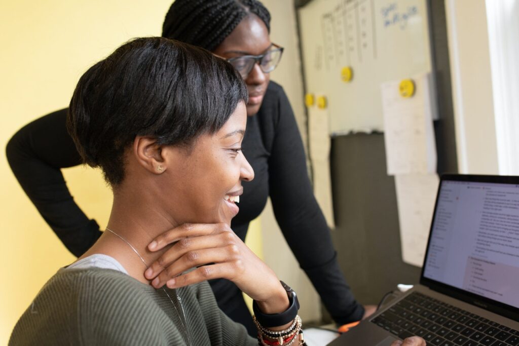 Women in office, smiling and browsing computer