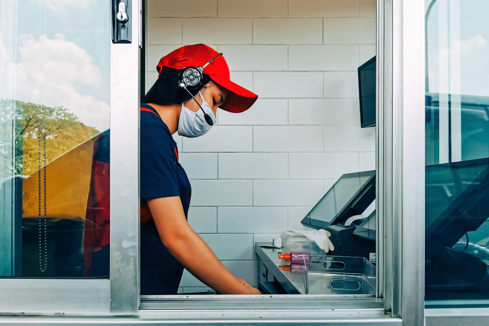 Worker wearing mask at serving fast food restaurant window