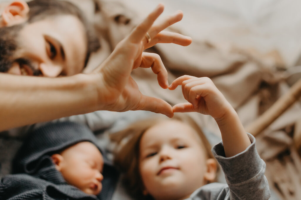 Father with two small children making heart shape with thumb and pointer finger