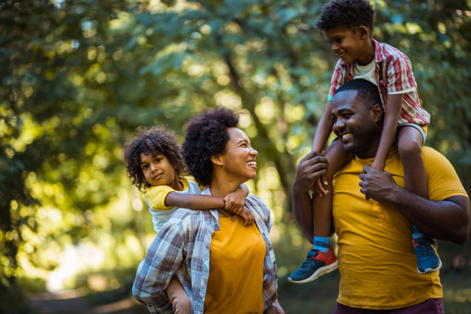 Parents carrying children on piggyback through park