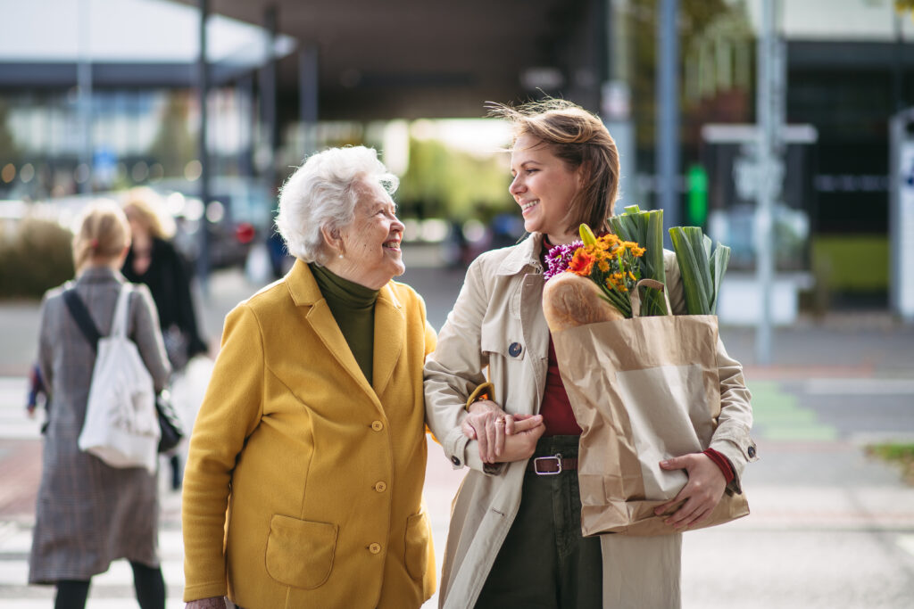 Granddaughter carrying groceries out to grandmother's car