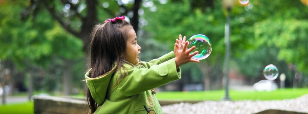 A stock image of a young girl playing with a bubble