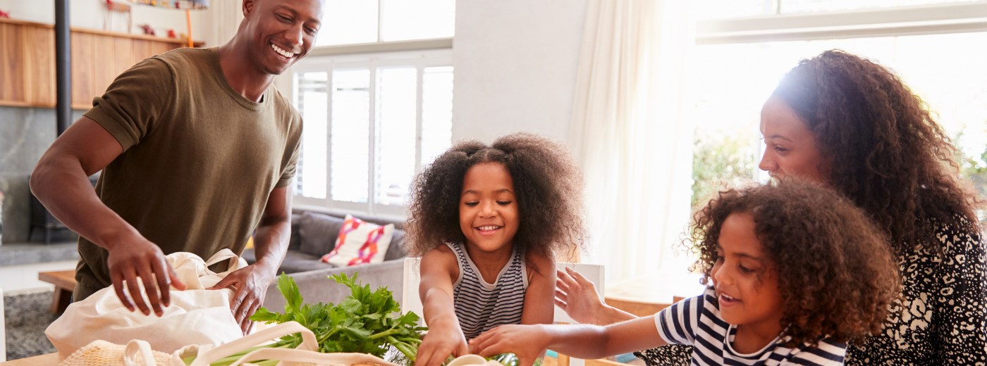 A stock image of a family smiling in the kitchen.