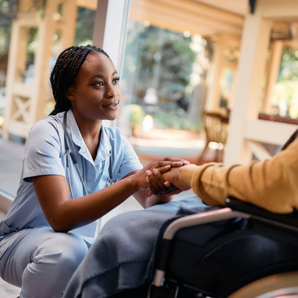 nurse holding elderly patient hands in wheelchair