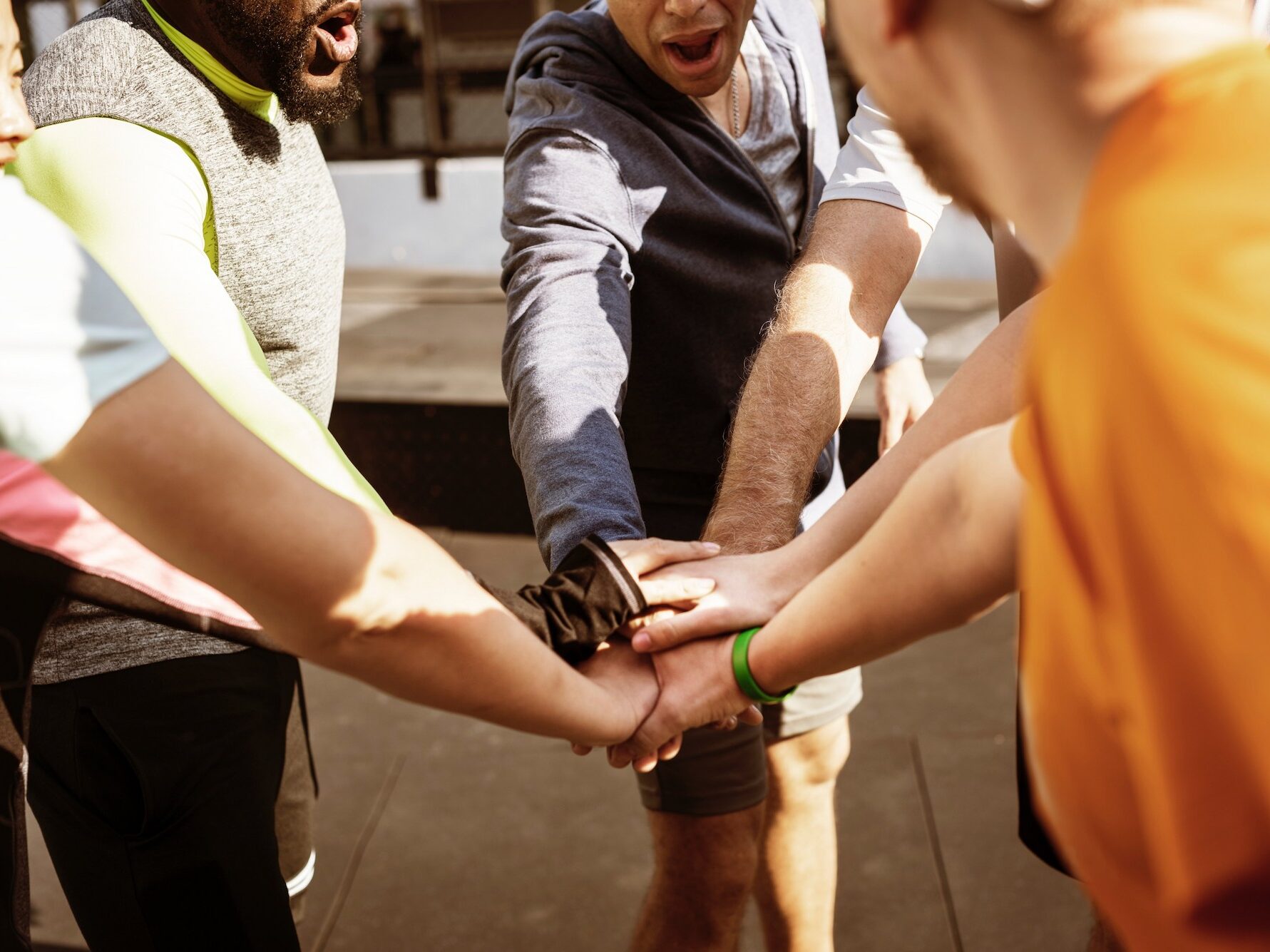 Multiple individuals holding hands together in a sign of teamwork