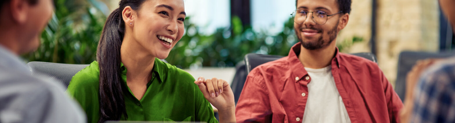 Woman wearing green shirt talking in meeting with work colleagues