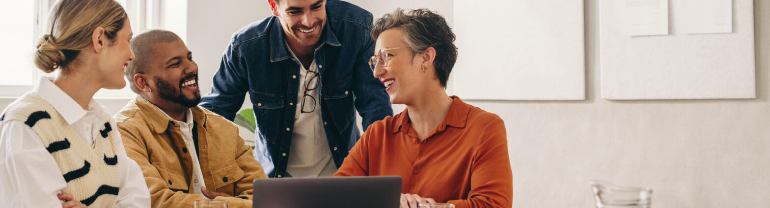 Four work colleagues in meeting group smiling